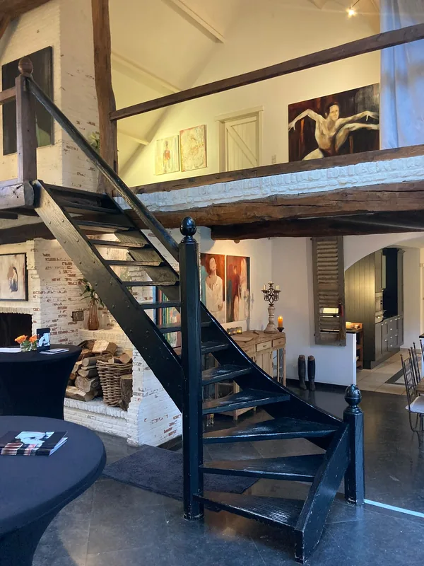 De trap en de mezzanine, met werken onder de balken.
