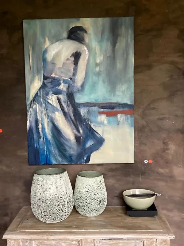 Een vrouw in een blauwe jurk, boven twee witte vazen.